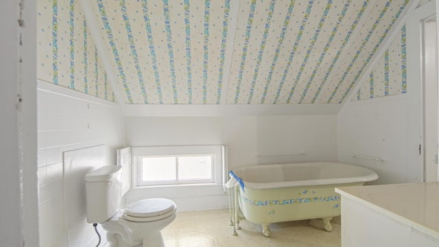 bathroom featuring a bathing tub, vaulted ceiling, and toilet