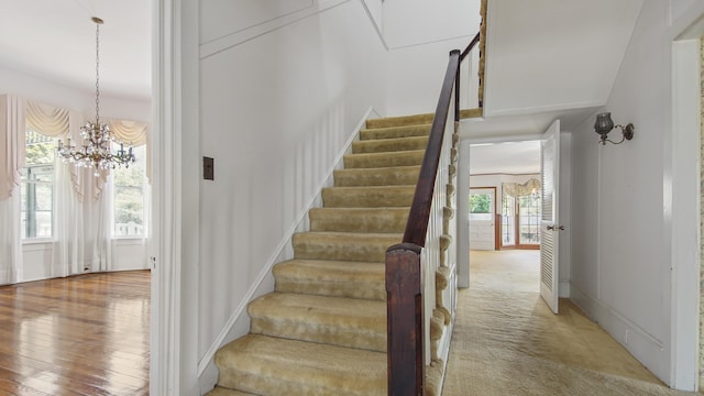 stairway featuring a chandelier, carpet floors, and a wealth of natural light