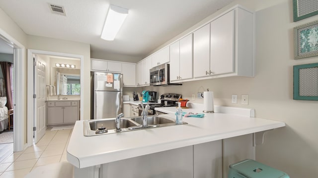 kitchen featuring stainless steel appliances, white cabinets, light tile floors, and kitchen peninsula