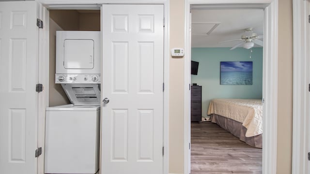 laundry area featuring stacked washer and dryer, light wood-type flooring, and ceiling fan