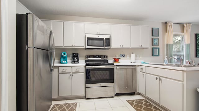 kitchen with sink, light tile floors, white cabinetry, and appliances with stainless steel finishes