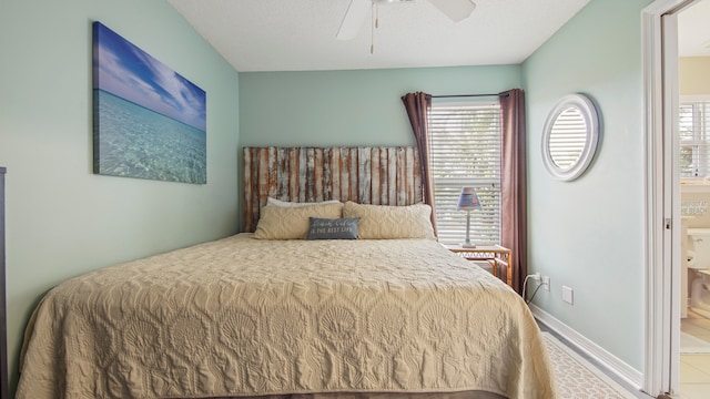 tiled bedroom with ensuite bath, ceiling fan, and multiple windows