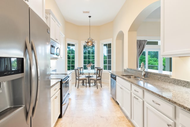 kitchen featuring decorative light fixtures, white cabinets, appliances with stainless steel finishes, sink, and light stone counters