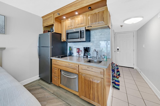 kitchen featuring decorative backsplash, sink, light hardwood / wood-style floors, and appliances with stainless steel finishes