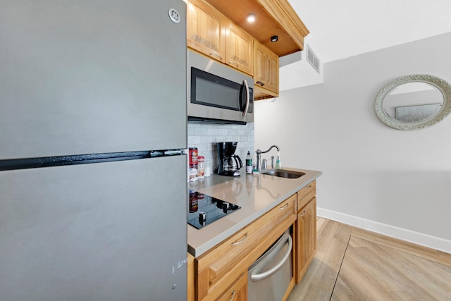 kitchen with appliances with stainless steel finishes, backsplash, sink, light brown cabinets, and light hardwood / wood-style floors