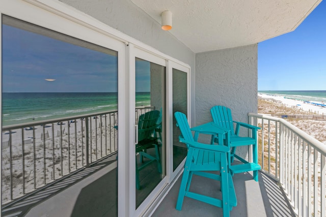 balcony with a water view and a view of the beach