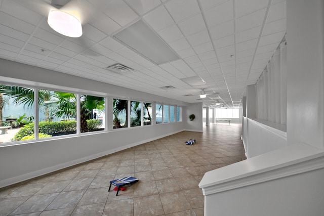 interior space with a paneled ceiling, light tile patterned floors, and a wealth of natural light