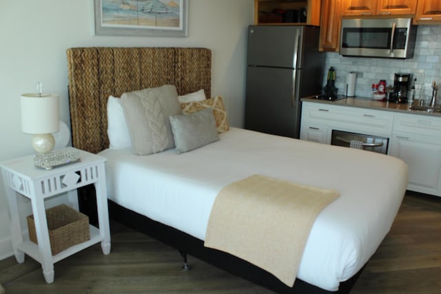 bedroom with stainless steel fridge, sink, and dark hardwood / wood-style floors