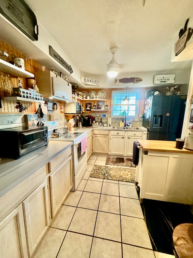 kitchen featuring black fridge with ice dispenser, ceiling fan, white electric stove, light tile flooring, and sink