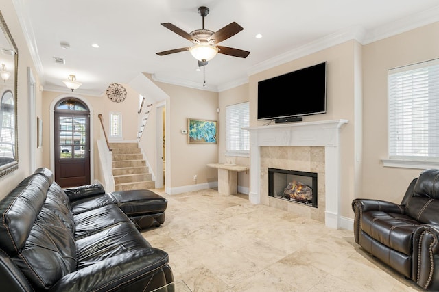 tiled living room featuring a tile fireplace, ceiling fan, and crown molding