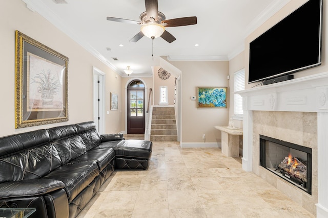 tiled living room featuring ceiling fan, a tile fireplace, and ornamental molding