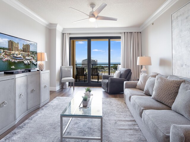 living room with ornamental molding, wood-type flooring, ceiling fan, and a water view