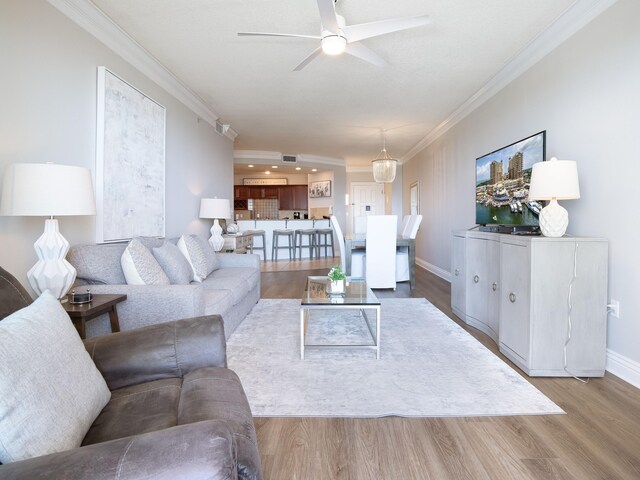 living room with ceiling fan, hardwood / wood-style flooring, and ornamental molding