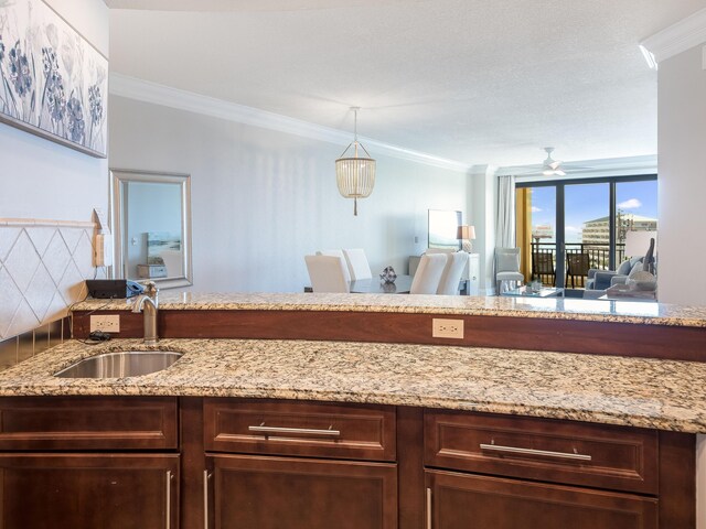 kitchen featuring sink, tasteful backsplash, ornamental molding, and light stone counters