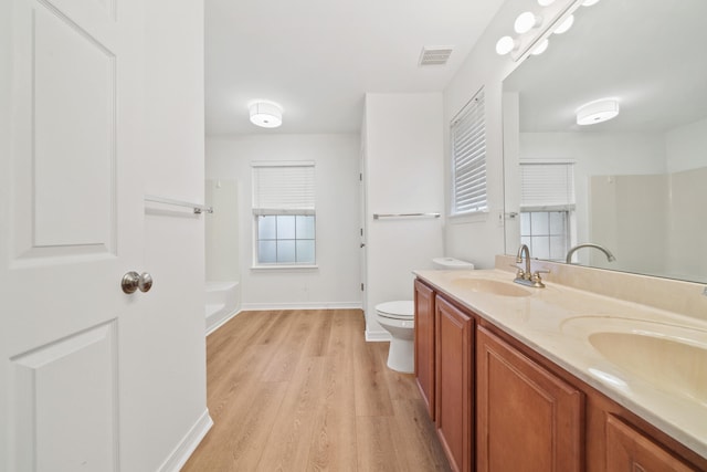 bathroom with hardwood / wood-style flooring, toilet, and double sink vanity