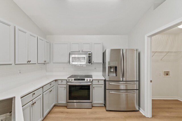 kitchen featuring decorative backsplash, stainless steel appliances, vaulted ceiling, and light hardwood / wood-style flooring