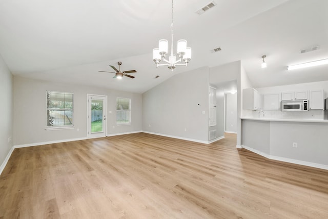 unfurnished living room featuring lofted ceiling, ceiling fan with notable chandelier, and light wood-type flooring