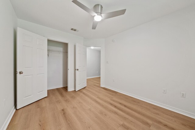 unfurnished bedroom featuring ceiling fan, light hardwood / wood-style floors, and a closet