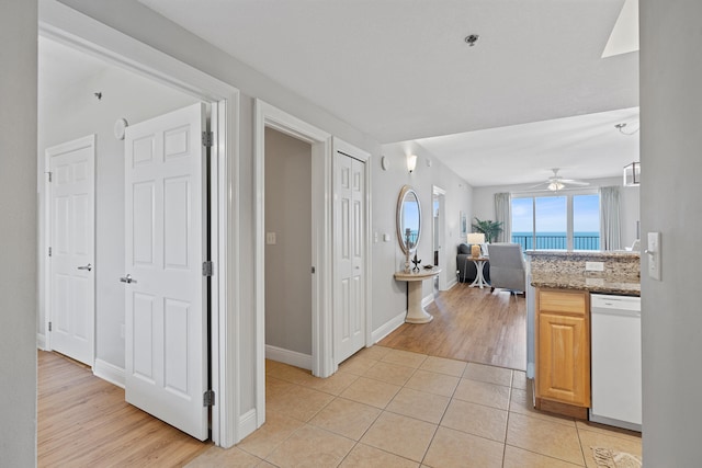 kitchen featuring white dishwasher, stone countertops, light tile flooring, ceiling fan, and light brown cabinets