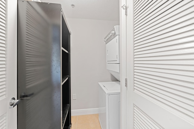 washroom featuring stacked washer / drying machine and light tile flooring