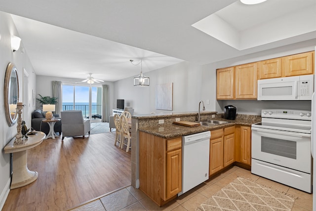 kitchen featuring a water view, light hardwood / wood-style flooring, ceiling fan, sink, and white appliances