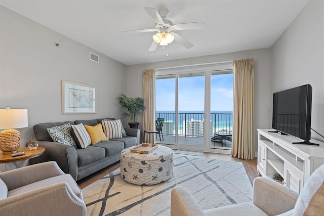 living room with ceiling fan, light hardwood / wood-style flooring, and a water view