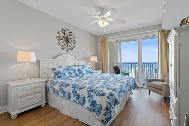 bedroom featuring a water view, ceiling fan, hardwood / wood-style flooring, and access to exterior