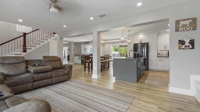 living room featuring ceiling fan with notable chandelier and light hardwood / wood-style floors