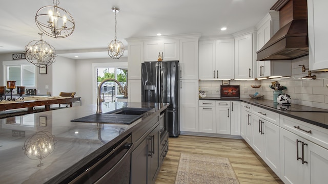 kitchen with fridge with ice dispenser, white cabinets, decorative light fixtures, and custom exhaust hood