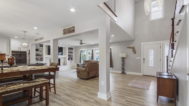 interior space with ceiling fan with notable chandelier, a large fireplace, and light hardwood / wood-style flooring