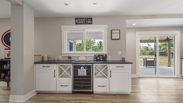 bar with light wood-type flooring, white cabinetry, and wine cooler