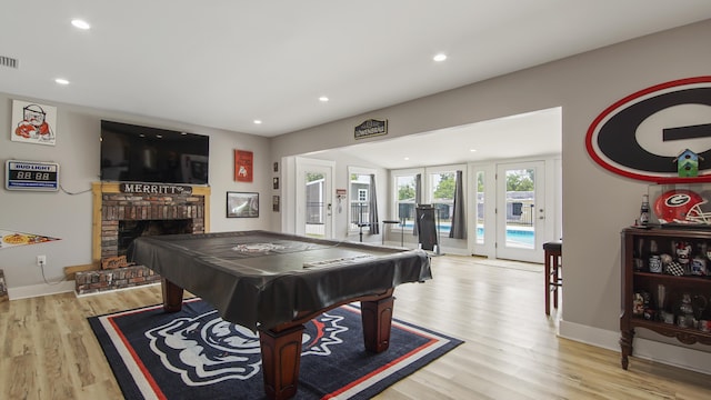 recreation room featuring a fireplace, pool table, french doors, and light hardwood / wood-style flooring