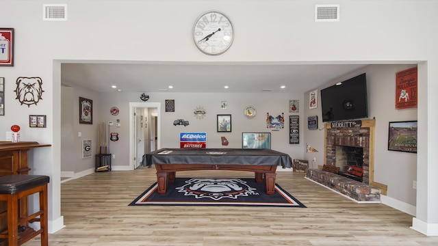 recreation room featuring light hardwood / wood-style floors, a fireplace, and pool table