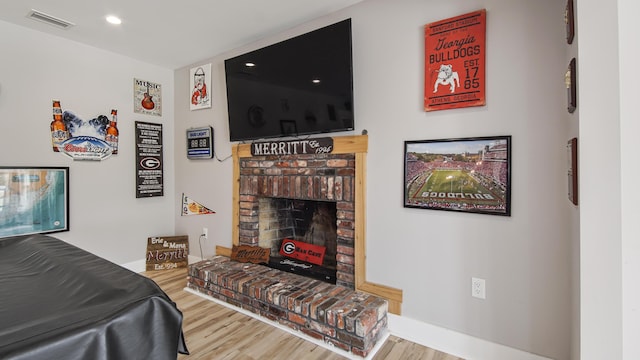 bedroom featuring hardwood / wood-style floors and a brick fireplace