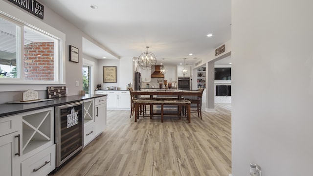 kitchen with wine cooler, oven, decorative light fixtures, white cabinets, and custom exhaust hood