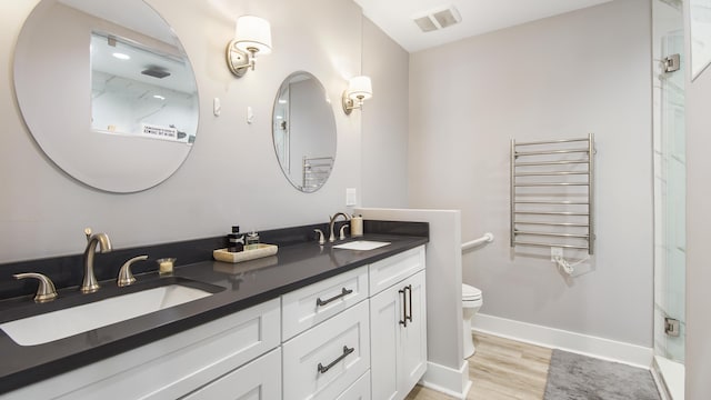 bathroom featuring radiator, an enclosed shower, toilet, vanity, and hardwood / wood-style flooring