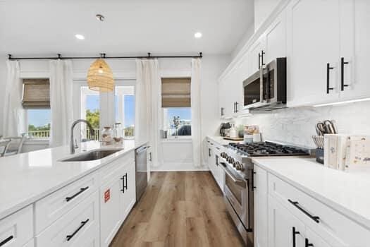 kitchen featuring white cabinets, hardwood / wood-style floors, appliances with stainless steel finishes, sink, and tasteful backsplash