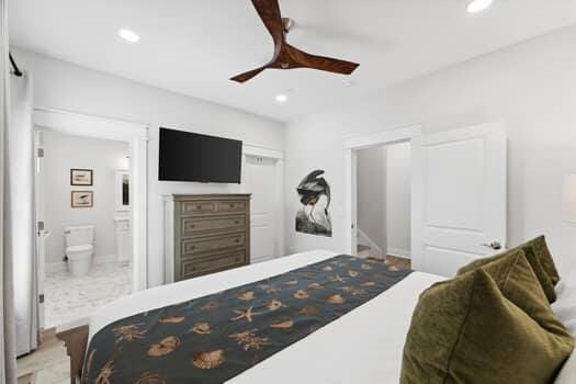 tiled bedroom featuring connected bathroom and ceiling fan