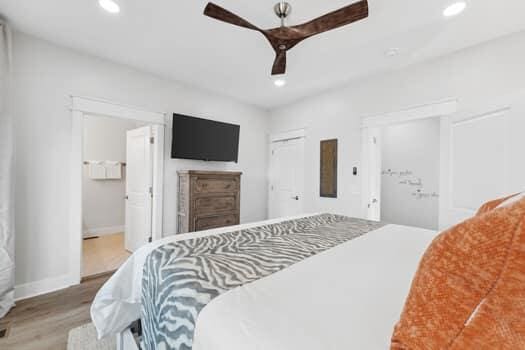 bedroom with connected bathroom, ceiling fan, and hardwood / wood-style flooring