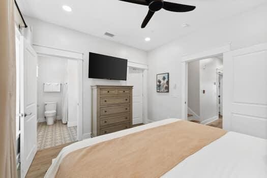 bedroom featuring ceiling fan, ensuite bathroom, and light tile floors