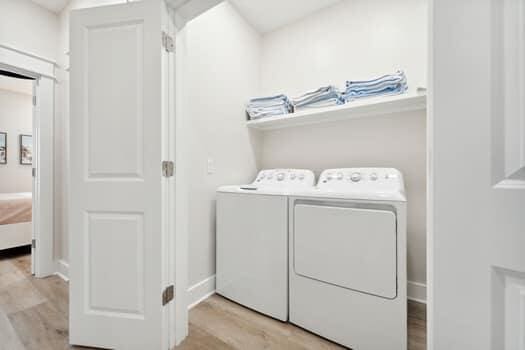 laundry area with light hardwood / wood-style floors and washing machine and clothes dryer