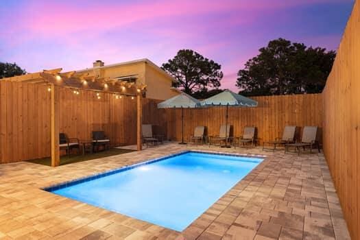 pool at dusk with a patio area