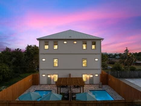 back house at dusk with a fenced in pool