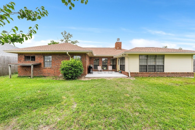 rear view of property featuring a lawn and a patio area