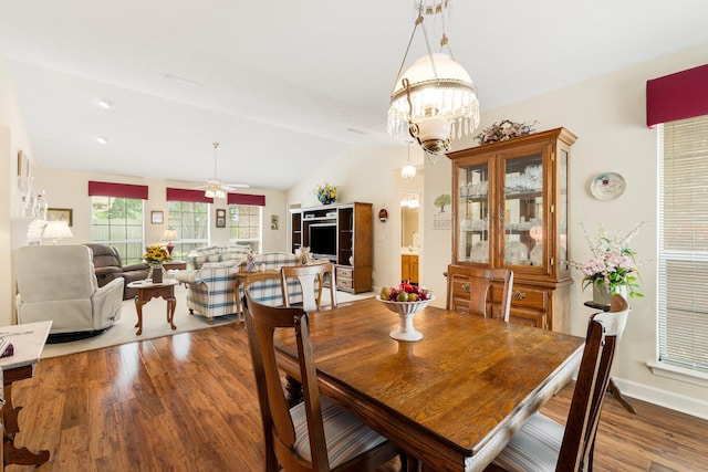 dining area with ceiling fan with notable chandelier, lofted ceiling, and hardwood / wood-style floors