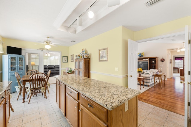 kitchen featuring ceiling fan, a kitchen island, rail lighting, light hardwood / wood-style flooring, and light stone countertops