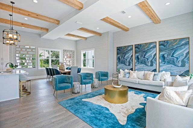 living room featuring beam ceiling, a chandelier, sink, and hardwood / wood-style floors