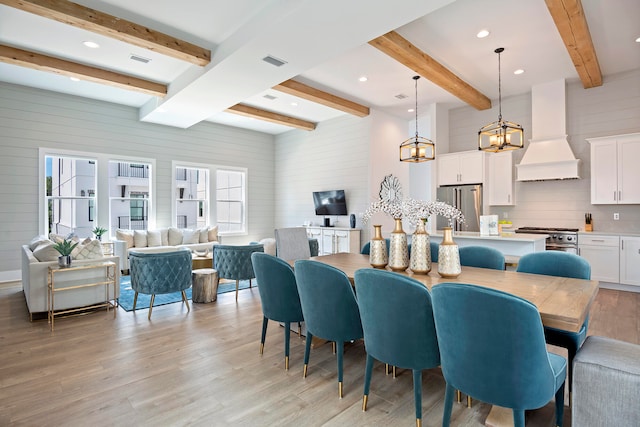 dining room with a notable chandelier, beam ceiling, plenty of natural light, and light hardwood / wood-style floors