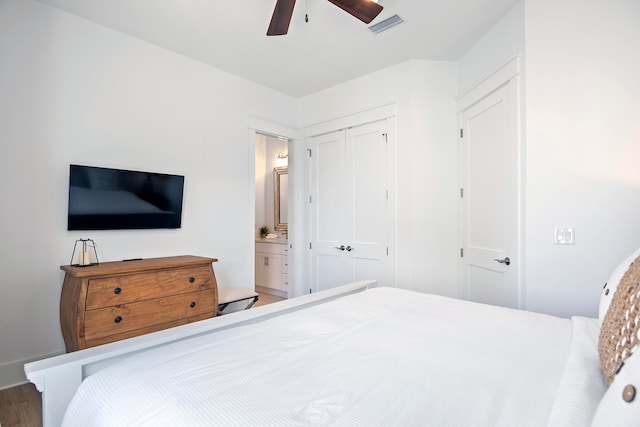 bedroom featuring wood-type flooring, ensuite bath, ceiling fan, and a closet