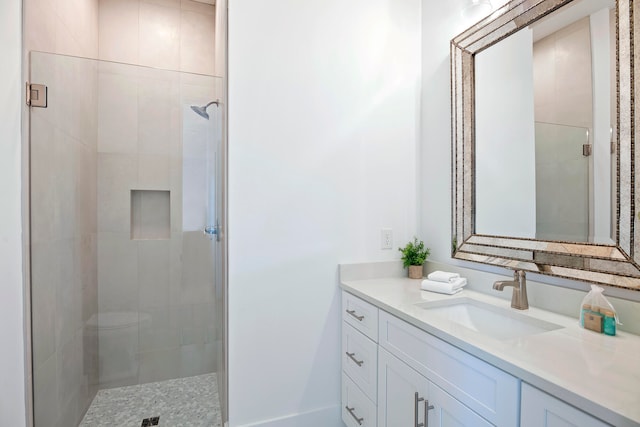 bathroom with tiled shower, toilet, and large vanity